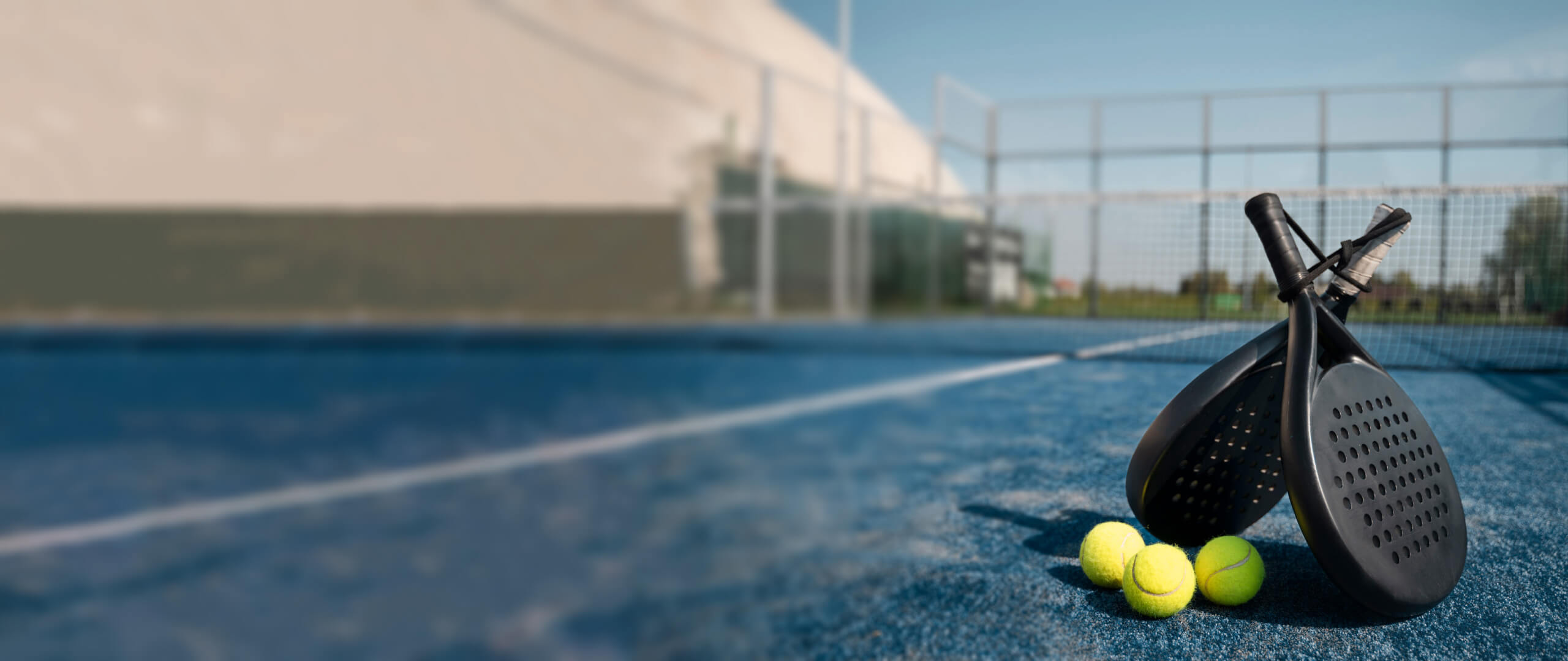 High-quality padel gear on an outdoor court, featuring two rackets and balls, perfect for a guide on choosing the right equipment.